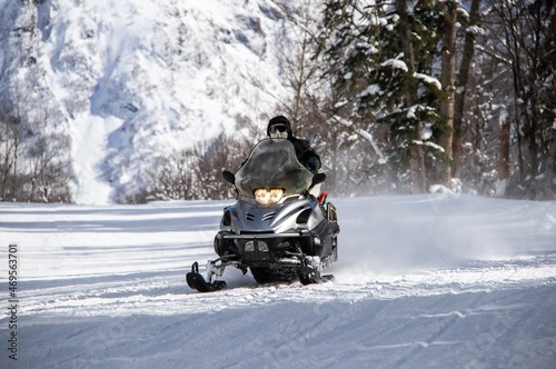 black snowmobile rides on a snowy road in the Caucasus mountains
