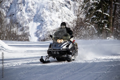 black snowmobile rides on a snowy road in the Caucasus mountains