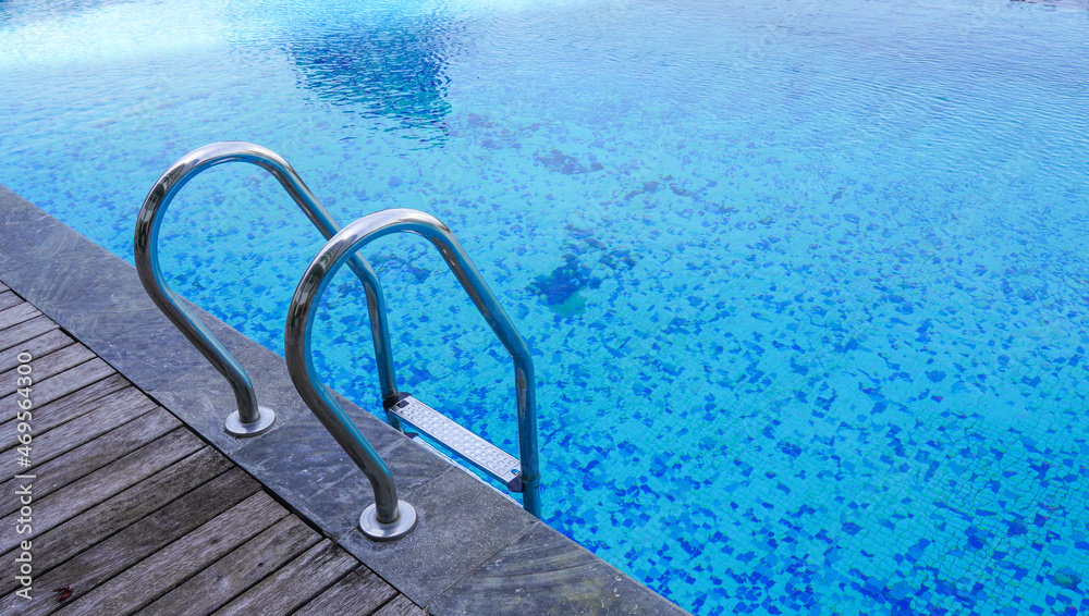 a swimming pool with limpid water having a hand railing on the edge. holiday with swimming and enjoying summer concept. a public pool.
