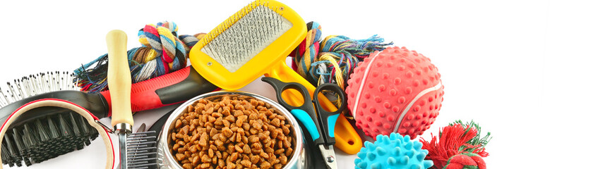 Pet accessories concept. Dry food, collars and rubber toys for pet on isolated white . Wide photo.