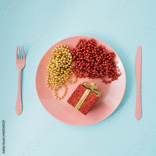 Creative flat lay with pink plate with cutlery, spoon kinfe and fork , abstract Christmas decoration on colored background pink and light blue. Retro aesthetic style. New Year party props  photo