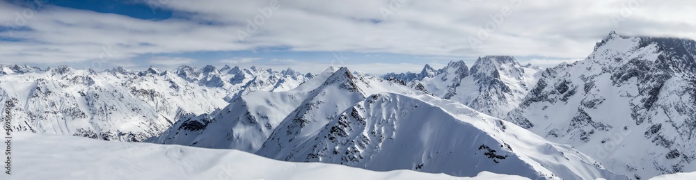 Panoramic view of snowy mountains peaks in the clouds blue sky Caucasus