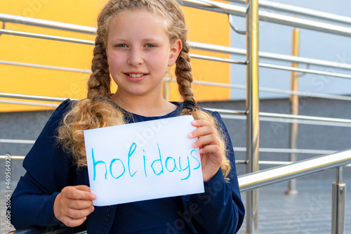  girl holding  paper with the words . Concept School holidays,graduation.  girl in a  uniform. pupil, learner, scholar. happy schoolgirl photo