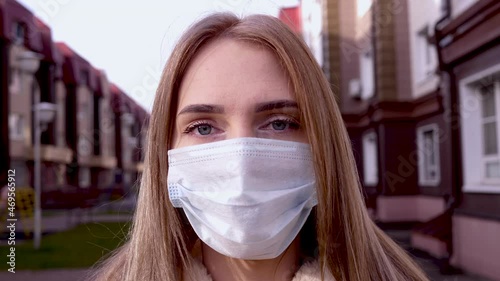 Portrait of a young girl in a medical mask from the Covid-19 pandemic looks at the camera