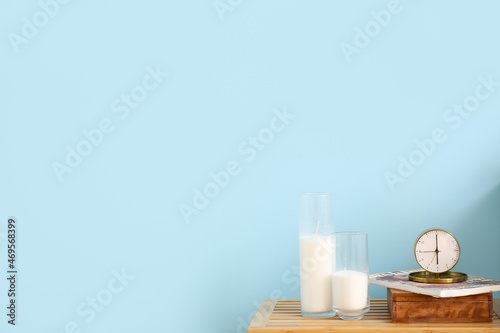 Alarm clock, magazine and candles on table near color wall