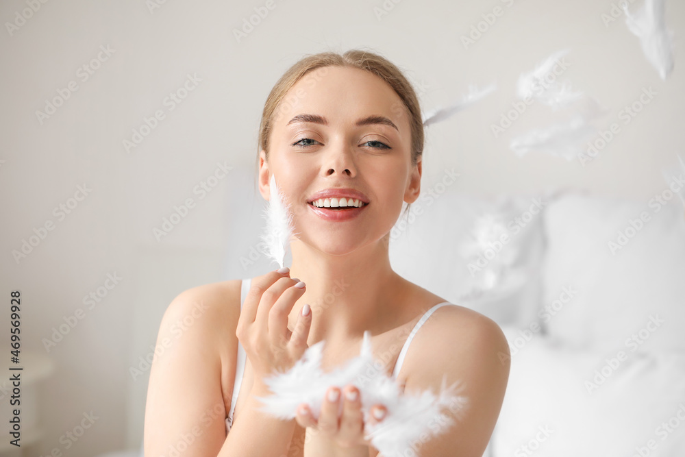 Beautiful young woman with soft feathers in bedroom Beautiful young woman with soft feathers in bedroom