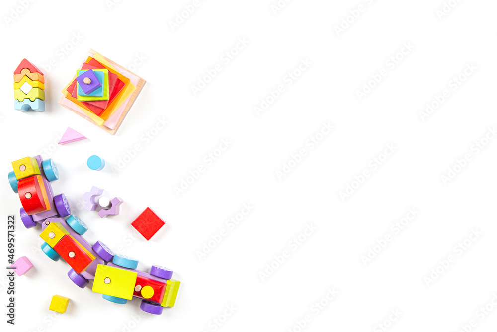Baby kids toys background. Top view to wooden toy train, wood stacking pyramid tower and colorful wood bricks on white background. Early education, zero waste, Montessori toys for children