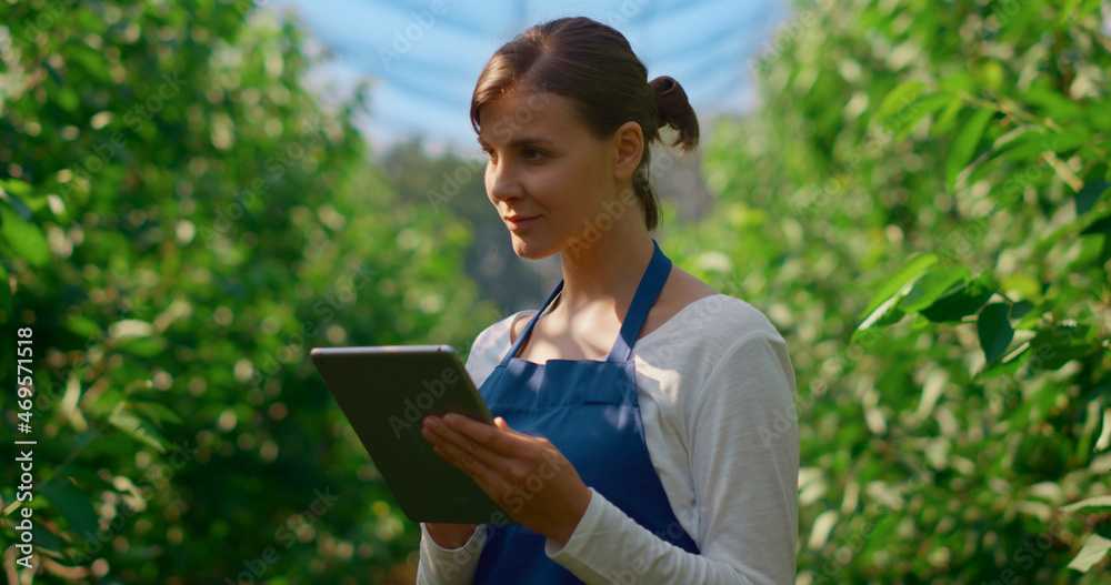 Fototapeta premium Woman farmer collecting data with modern device in green plantation smiling