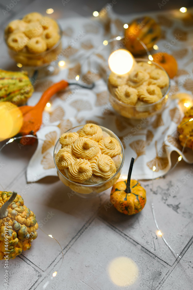 Pumpkin tiramisu in bowls on a light table with a garland and decorative pumpkins. Flat lay. Pumpkin tiramisu in bowls on a light table with a garland and decorative pumpkins. Flat lay.