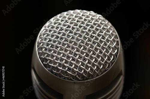 Professional microphone in a music studio on a black background. Record sounds and songs. Chrome metal microphone. Digital recorder and technology. Musical equipment. Close-up © sb2010