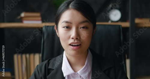 Surprised Asian business woman looks at the camera in surprise and says wow while sitting in the office. A shocked female student in formal suit rejoices at the good news, indoors