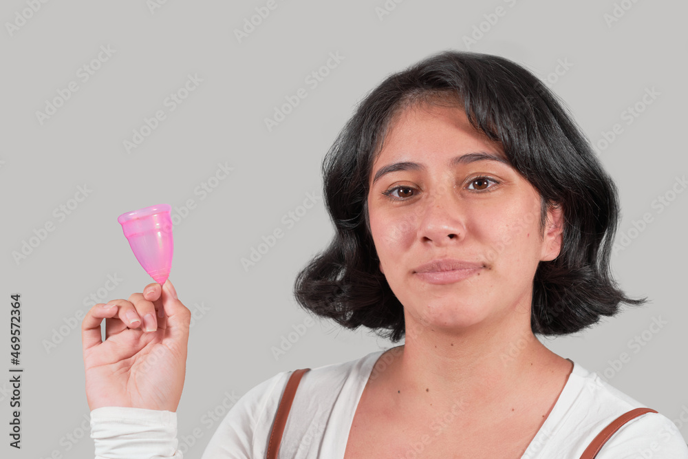 Portrait of young latin woman holding menstrual cup, isolated. Portrait of young latin woman holding menstrual cup, isolated.