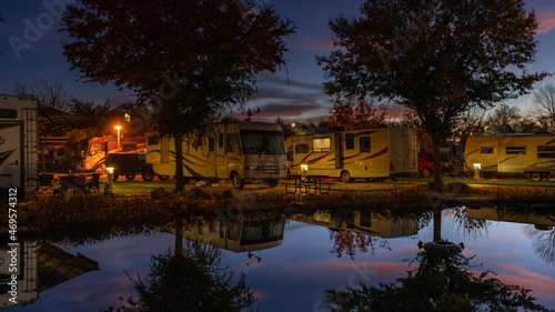 Reflection in the pond of the campers parked next to it in the very early morning sunrise with a colorful sky above