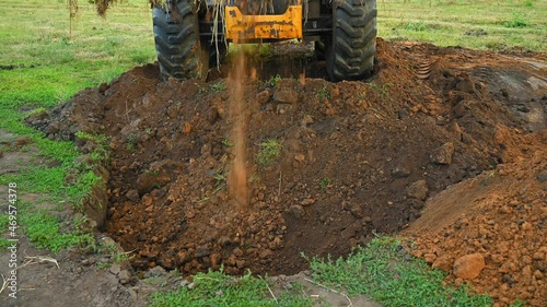 Earthworks in the countryside. Modern bulldozer burying a trench at a construction site. Summer cloudy day