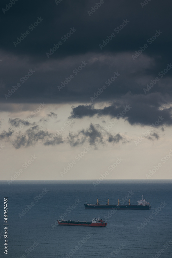 Aerial view of a single big cargo ship on the sea over cloudy blue sky