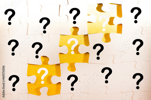 question marks and white jigsaw puzzle pieces on a yellow background. FAQ, Business solution concept