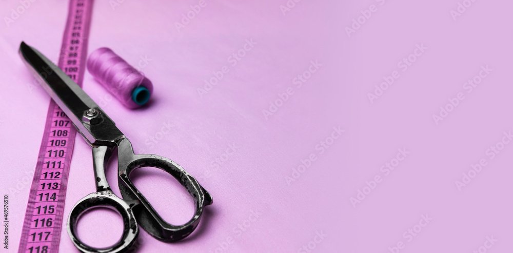 Spool of thread, centimeter and sewing scissors on a pastel purple background. Models for tailors or textile workshops. Empty space for text. Spool of thread, centimeter and sewing scissors on a pastel purple background. Models for tailors or textile workshops. Empty space for text.