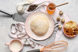 Plate with fresh dough and ingredients for preparing homemade cookies on light background