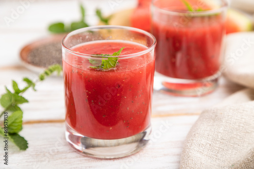 Watermelon juice with chia seeds and mint in glass on a white wooden background with linen textile. Side view, selective focus.