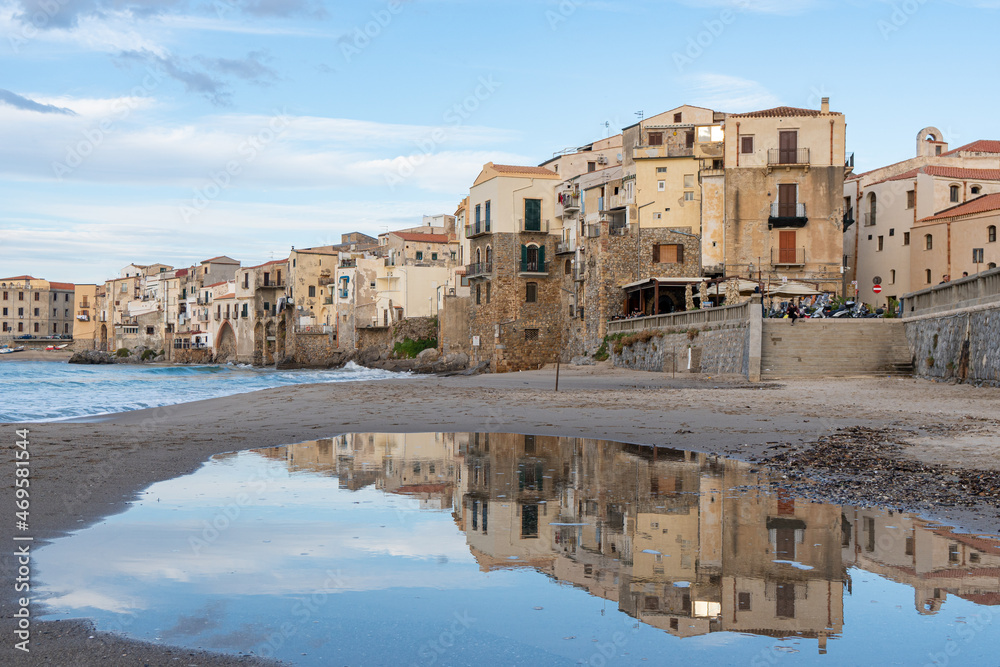 Cefalù's Reflective Shore. The historic buildings of Cefalù are mirrored beautifully in the calm waters, creating a dreamy landscape of this enchanting town.