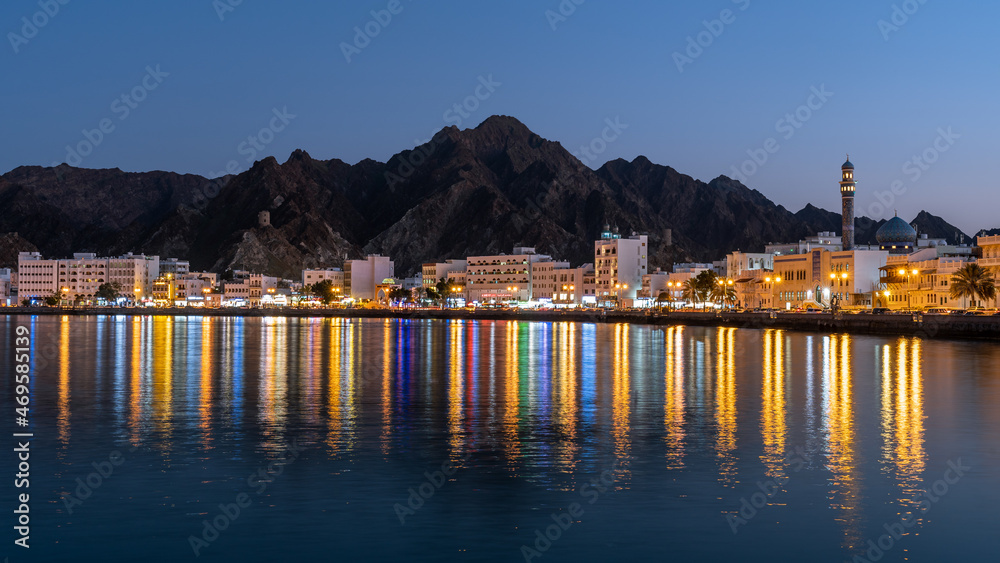 View of the harbour of Muscat with colourful reflecting city lights at night