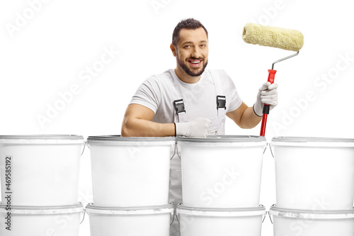 House painter standing behind a pile of buckets and holding a paint roller