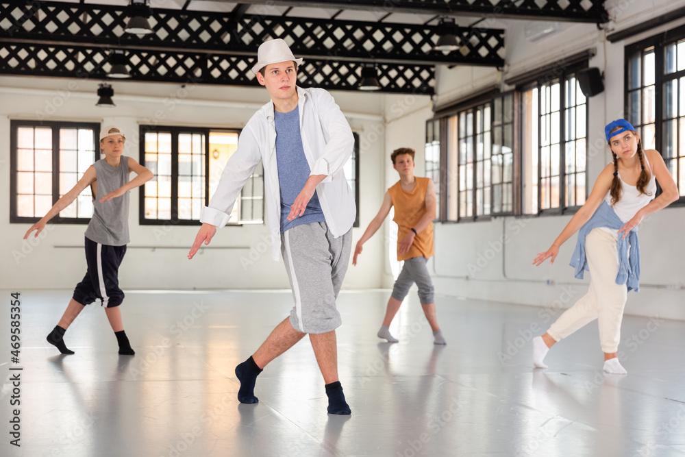 Group of teenagers practicing active dance movements at dance class