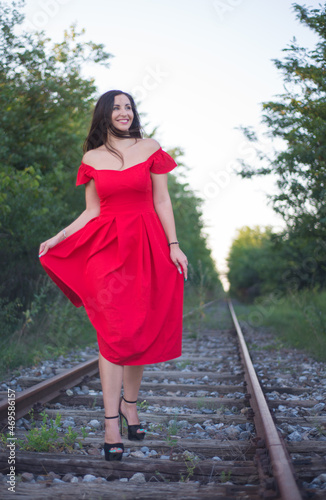 A girl in a red dress on the railroad tracks