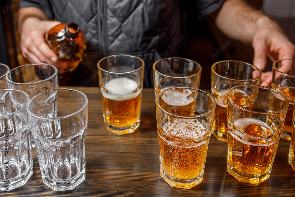 The bartender pours beer into a glass from a plastic bottle. The bartender pours beer into a glass from a plastic bottle.
