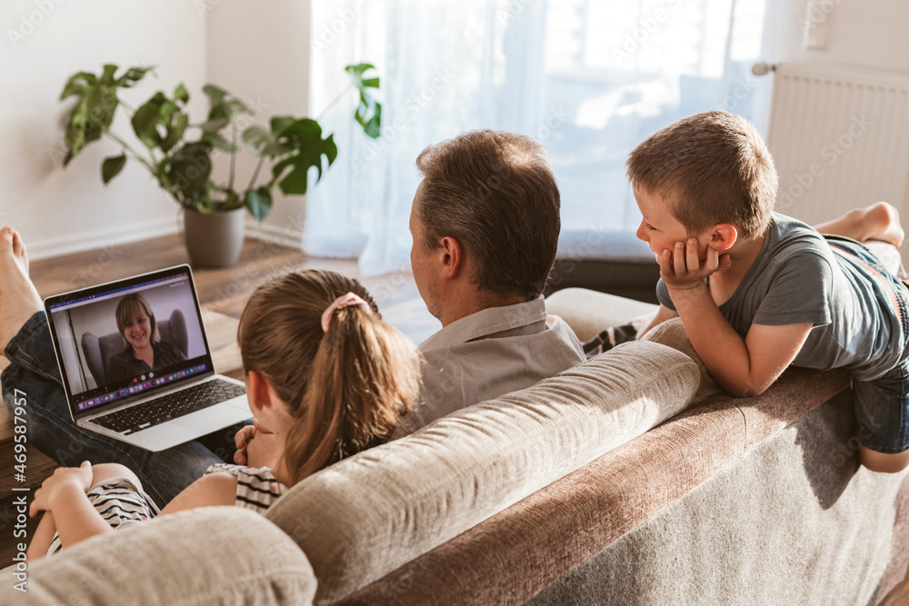 Video call using laptop from home. Dad and children sit on the couch and call mom online. Communication at a distance Video call using laptop from home. Dad and children sit on the couch and call mom online. Communication at a distance