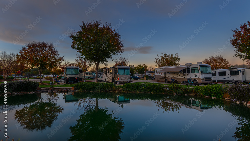 Reflection in the pond of the campers parked next to it in the early morning sunrise