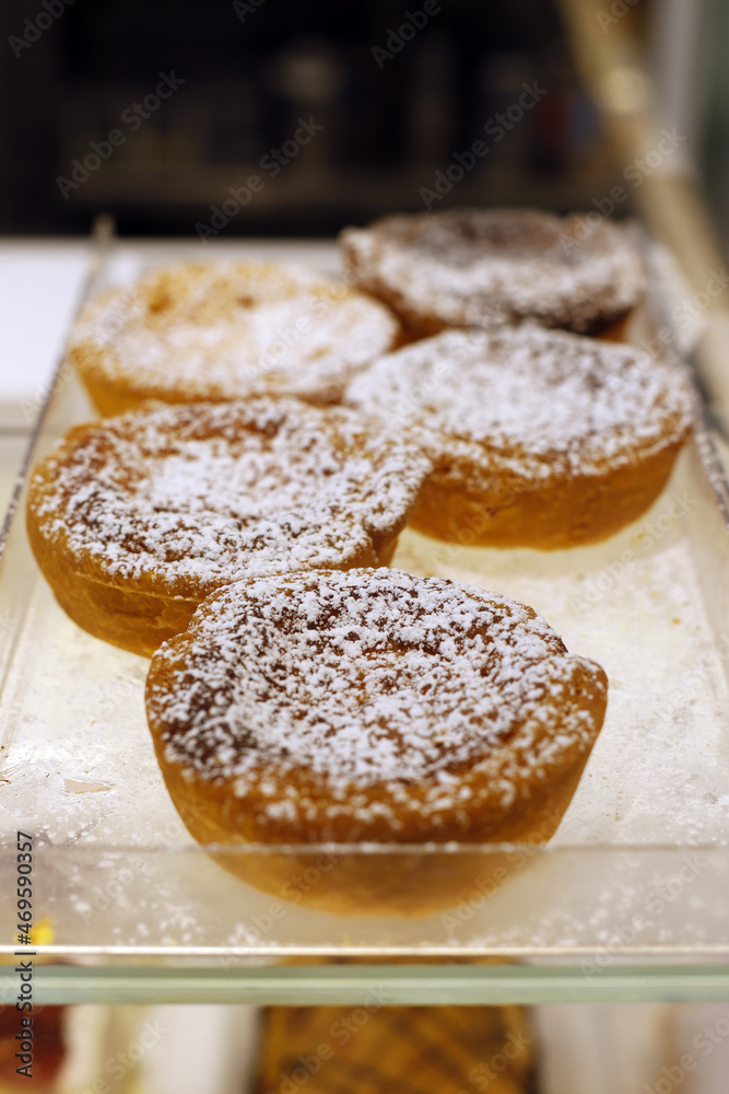 tartaletas portuguesas dulces con azúcar glas en bandeja de pastelería
