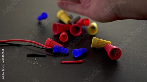 Hand is adding electrical wire connector to black background with wire