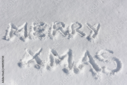 Hand drawn inscription Merry Christmas on white surface of snow. Greeting card. Christmas concept.Top view. Flat lay. © TetiBond