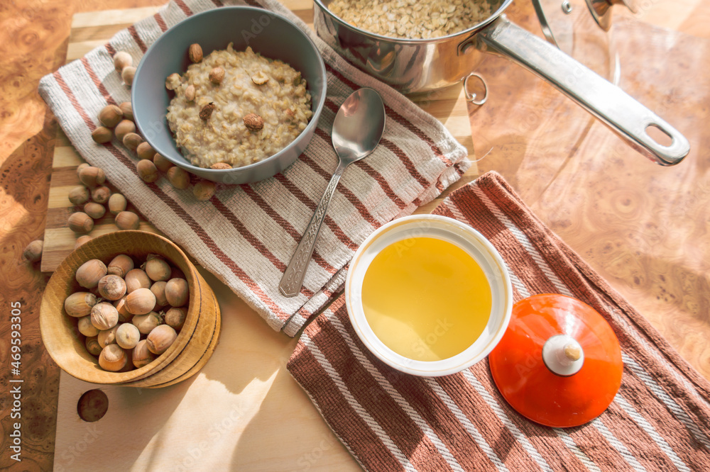 Healthy, dietary and nutritious oatmeal with delicious homemade honey, hazelnuts in a gray plate on the table top view. Healthy, dietary and nutritious oatmeal with delicious homemade honey, hazelnuts in a gray plate on the table top view.