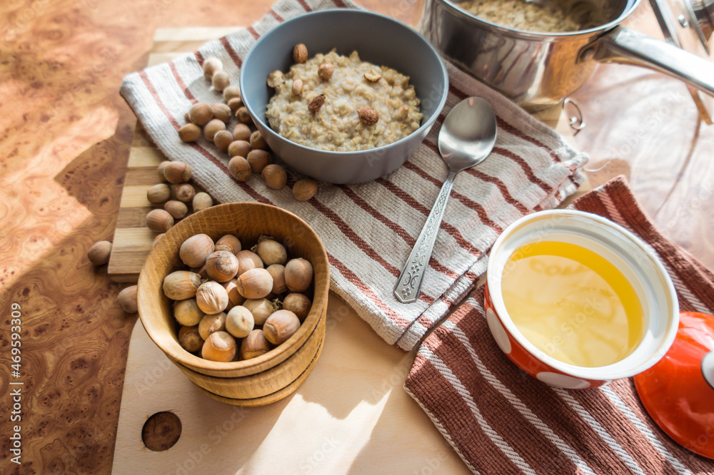 Healthy, dietary and nutritious oatmeal with delicious homemade honey, hazelnuts in a gray plate on the table top view. Healthy, dietary and nutritious oatmeal with delicious homemade honey, hazelnuts in a gray plate on the table top view.