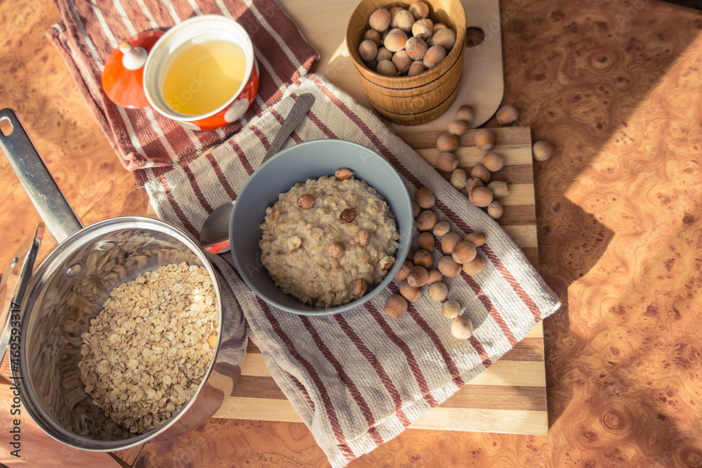 Healthy, dietary and nutritious oatmeal with delicious homemade honey, hazelnuts in a gray plate on the table top view. Healthy, dietary and nutritious oatmeal with delicious homemade honey, hazelnuts in a gray plate on the table top view.