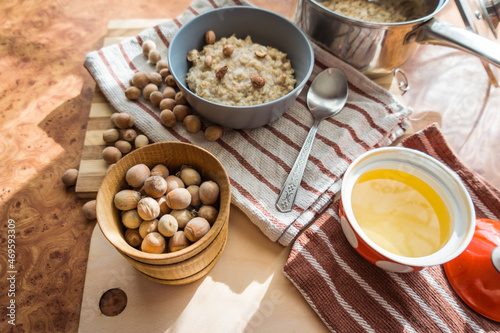 Healthy, dietary and nutritious oatmeal with delicious homemade honey, hazelnuts in a gray plate on the table top view.