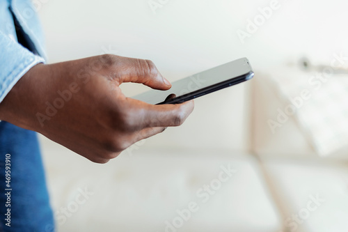 Cropped shot of an unrecognizable businessman standing alone in his home office and texting on his cellphone. Studio shot of an unrecognizable young man using his cellphone against a grey background.