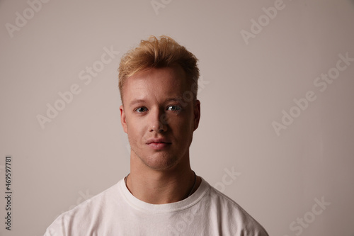 Portrait of a handsome young man sitting against white background wears t-shirt.