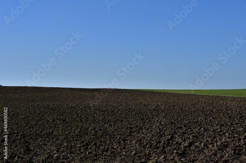 Leeres braunes Feld mit einem Stück grün und blauem Himmel im Herbst