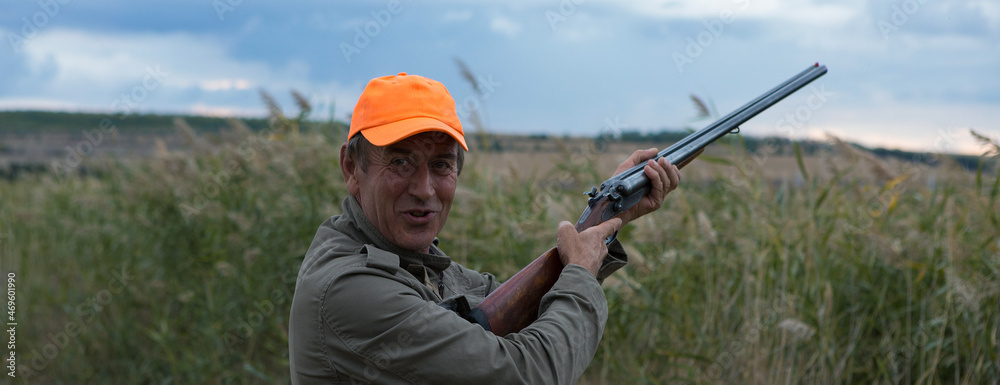 Duck hunter with shotgun walking through a meadow. Duck hunter with shotgun walking through a meadow.