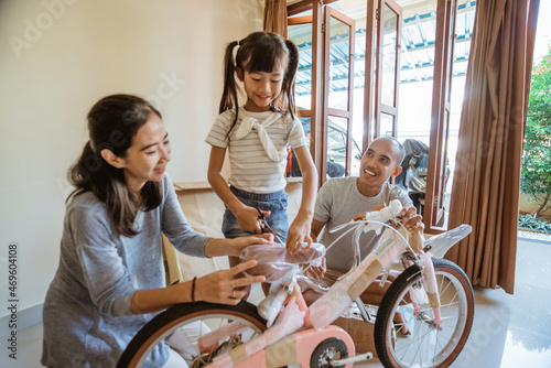 Daughter unwraps the plastic while holding the new mini bike photo