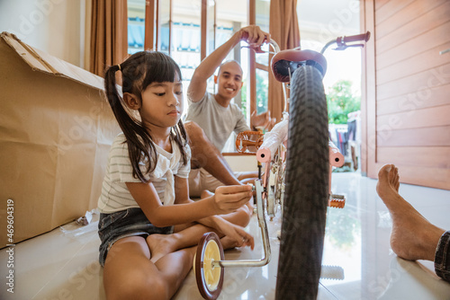 Foto Asian girl installs auxiliary wheel bolts on new mini bike