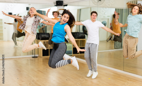 Group of teenagers jumping together during dance class in studio.
