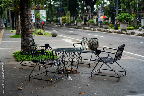 Empty public chairs in a park of Dago Street sidewalk during the pandemic, with a few trash strewn around it photo