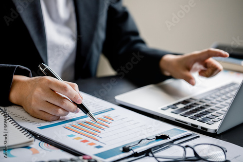 Close up of Businesswomen or Accountant using a laptop computer with analyzing business report graph and finance chart at the workplace, financial and investment concept.