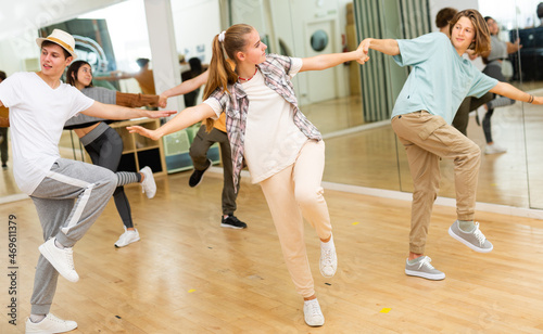 Sporty cheerful teenagers learning to dance vigorous jive in pairs in choreography class.