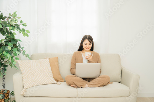 家でノートパソコンを使う女性（ソファ） 