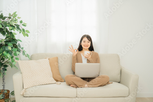 家でノートパソコンを使う女性（ソファ） 